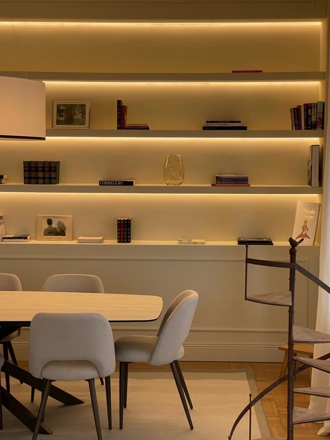 Zona pranzo con libreria retroilluminata e scala a chiocciola in ferro