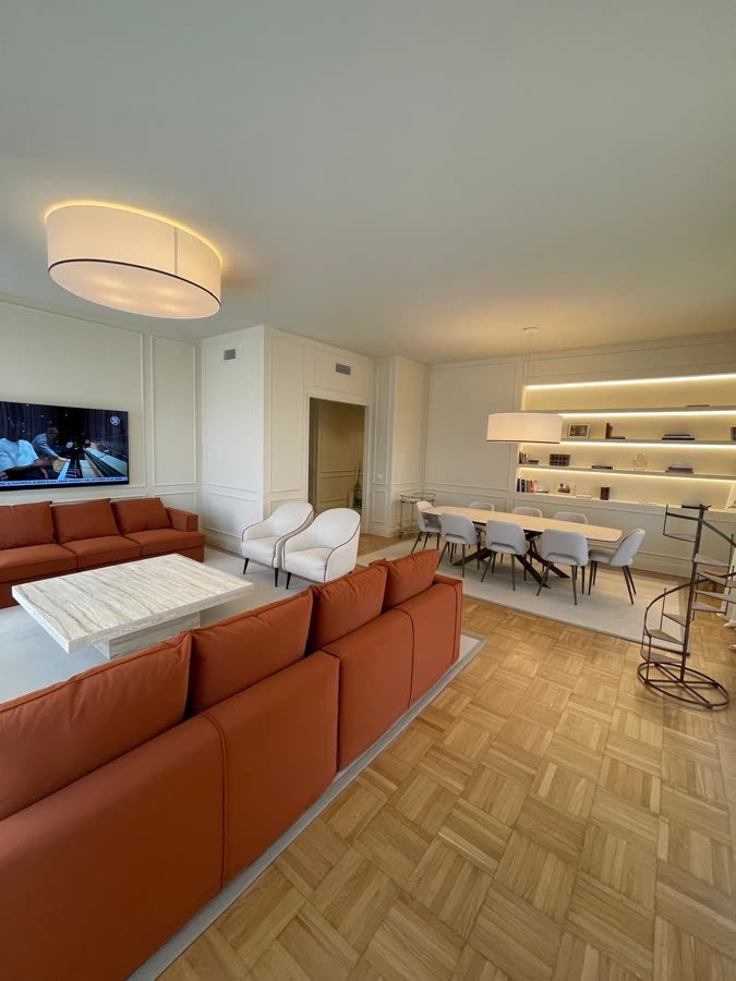 Salotto con divani terracotta, televisore a parete e parquet a quadri