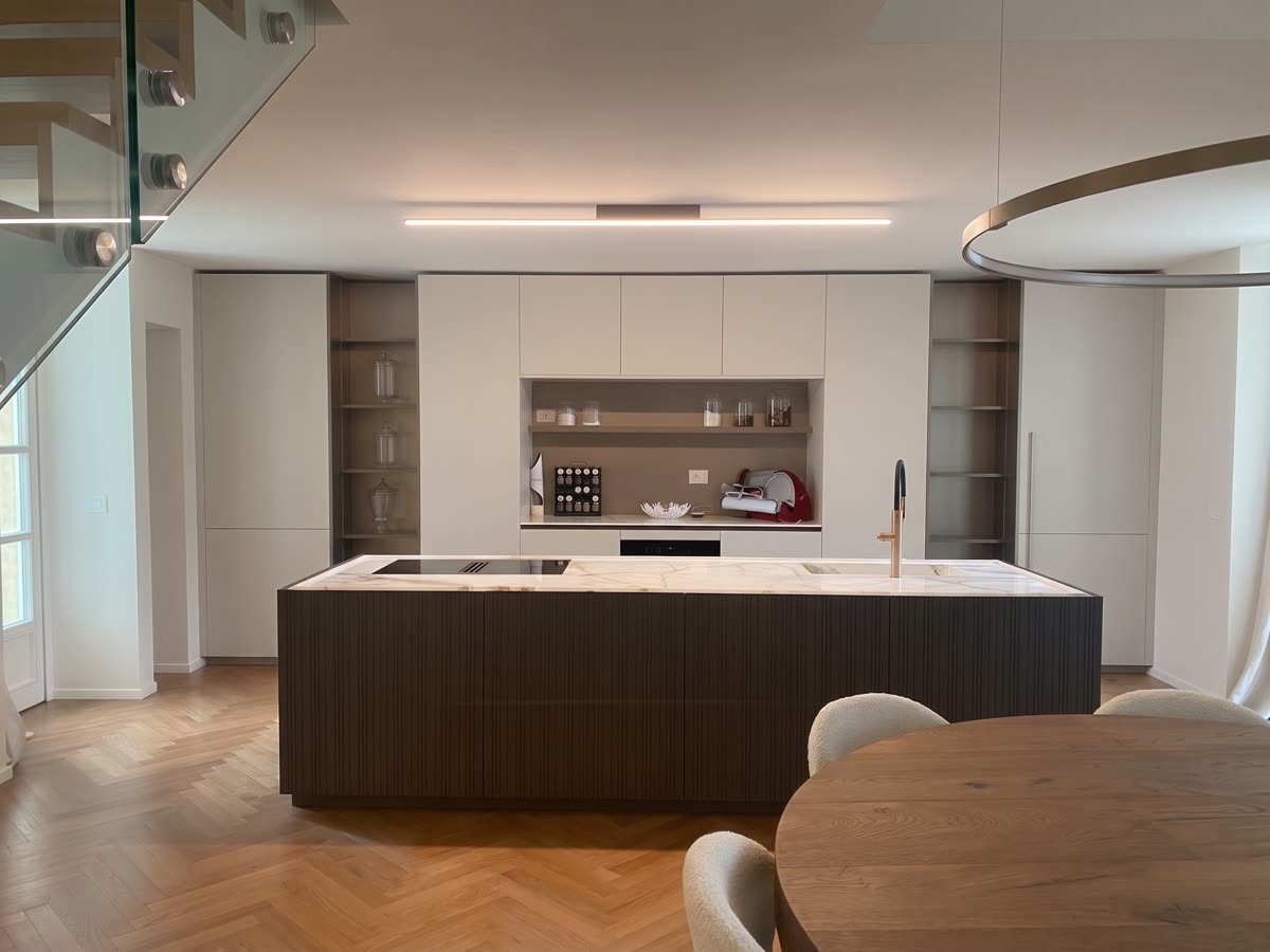 Cucina con isola scura e piano chiaro, parquet a spina