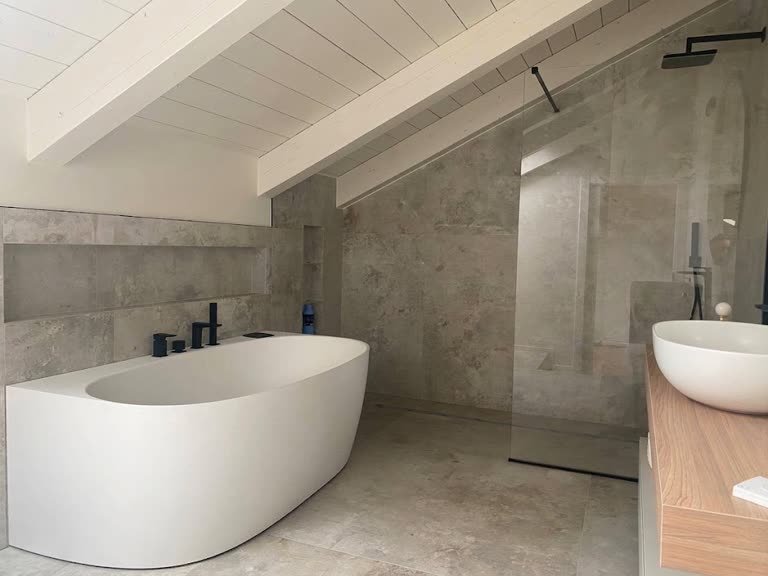Bagno sottotetto con vasca freestanding e rivestimento in pietra