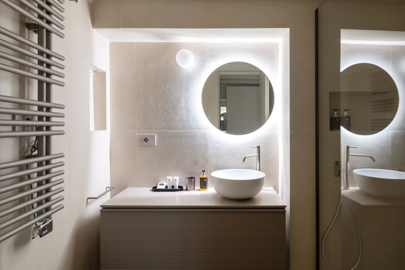 Bagno con specchio tondo retroilluminato e lavabo a bacinella