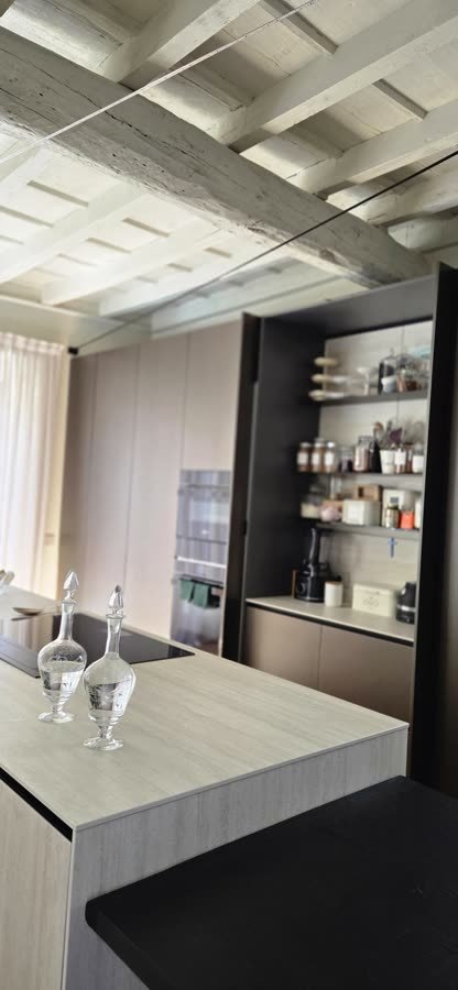 Cucina con isola chiara e dispensa a giorno