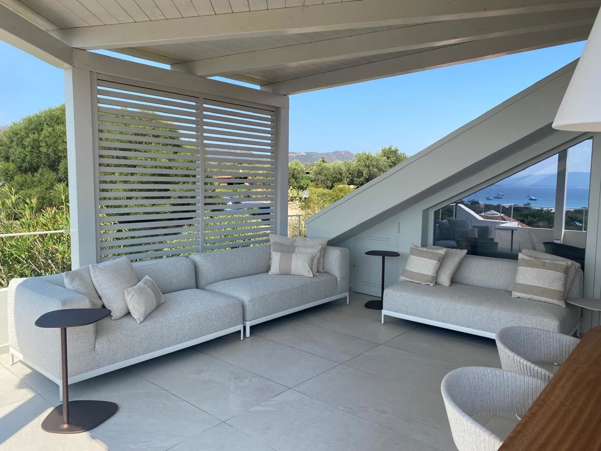 Terrazza coperta con frangisole, divano da esterno e vista sulle colline